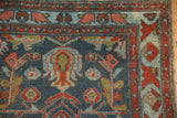 Distressed Mehreban rug corner, showing burgundy arabesque border and faded blue field design.