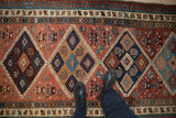 Black boots on vintage Serab runner, highlighting madder red diamond medallion pattern.