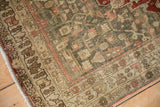 Corner detail of a distressed vintage Bijar rug showing sprawling vines and a time-softened texture.