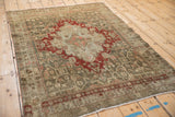 Angled view of a vintage Bijar rug highlighting its distressed character and geometric red medallion.