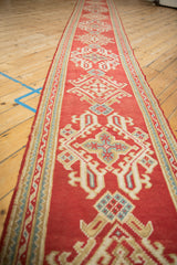 Side view of Oushak runner: cherry red field, ribboned border, and repeating medallions.