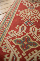 Cherry red Oushak runner detail: ribboned border and hook-and-latch quatrefoil motif in ivory and blue.