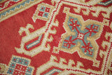 Close-up of vintage Oushak rug's cherry red field, ivory and sky blue quatrefoil motifs, even wear.