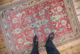A person's view of a distressed Anatolian rug with raspberry red and powder blue geometric palmettes.
