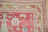 Corner of a distressed Anatolian rug with an ivory border featuring a reciprocating pawn design.