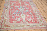 Angled view of the distressed Anatolian rug's raspberry red field and geometric central design.