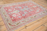 Angled view of a distressed Anatolian rug with a raspberry red field and geometric motifs.