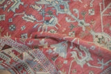 Close view of a folded vintage Anatolian rug showing its raspberry field, palmette motifs, and geometric border.