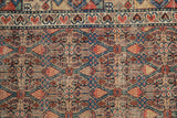 Close detail of an antique Persian Serab rug's geometric lattice in camel, indigo, and madder root red.