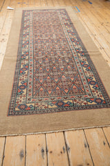 Full length angled view of an antique camel hair Serab runner with a prominent plain border.