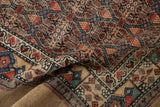 A folded corner of the antique Serab runner reveals the textured camel hair pile and detailed lattice design.
