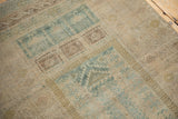Distressed Belouch rug texture showing muted dusty teal hook and latch geometric patterns, even wear.