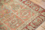 Angled view of the distressed Bakhtiari rug's low pile and raspberry red arabesque border.