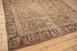 Angled view of a distressed Baktiari rug highlighting the red arabesque border and panelled field.