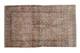 Vintage distressed Sarouk rug with a floral medallion in faded raspberry red, olive green, and dusty blue tones.