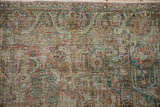 Detailed view of a vintage Sarouk rug's worn pile, showing exposed knot heads and dusty motifs.