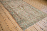 High-angle view of a distressed Sarouk rug with a muted raspberry, blush, and green palette.