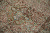 Storied, textured wear on a vintage Sarouk rug with dusty red and olive green floral details.