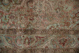 Detailed view of the distressed hand-knotted pile in dusty raspberry red and olive green.