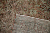 The hand-knotted construction and distressed pile of a vintage Sarouk rug.