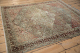 Angled view of a distressed Baktiari rug's intricate trellis panels and time-softened tones.