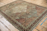 Angled perspective of a distressed Baktiari rug showing its trellis pattern in muted blues and reds.