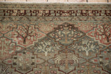 Close-up of the intricate border and worn pile on a vintage Baktiari rug with tree motifs.