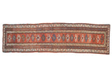 Antique Caucasian rug runner with a column of hook-and-latch medallions on a brick red field with intricate geometric borders.
