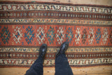 The time-softened low pile of an antique Caucasian runner with intricate hook-and-latch medallions.