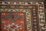 Corner detail of an antique Caucasian rug showing the crab style and meandering vine borders.
