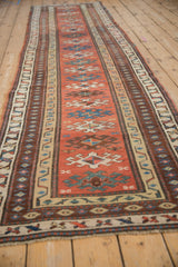 Angled view down the entire length of an antique Caucasian runner, showing its geometric pattern.