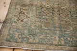 Distressed vintage Bijar rug corner showing worn pile, muted blue-green tones, and color abrashes.
