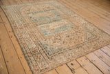 Distressed Qashqai rug corner: ivory, dusty blue border, minor lion spandrels, even wear.