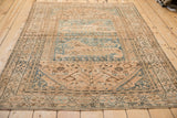 Distressed Qashqai rug corner showing textured pile, minor lion design, and continuous vine border.