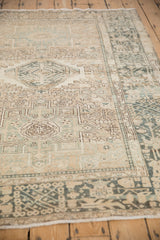 An angled view showing the intricate geometric border and worn texture of a vintage Karaja rug.