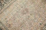 Angled view of the distressed Karaja rug's worn pile and geometric hook and latch medallion.