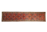 Antique Northwest Persian runner with an allover floral vine design in navy blue and teal on a tomato red field.