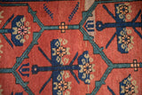 Detailed view of hand-knotted floral panels in navy, teal, and beige on the runner's red field.