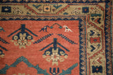 Stylized white animal figure and floral motifs on the pale tomato red field of an antique rug.