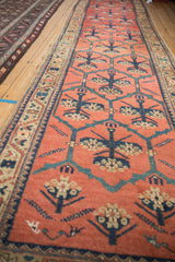 A long perspective of the antique Persian runner's repeating floral panels in blue on a red field.