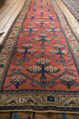 Angled view down the length of a Northwest Persian runner with repeating floral motifs on a tomato red field.