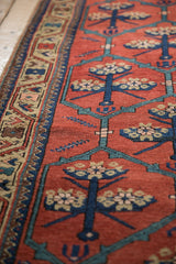 Angled close-up of the delineated floral panels and wool pile on an antique Persian runner.