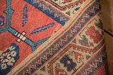 Detailed corner view of an antique Persian rug showing the low-pile texture and woven side selvage.