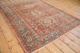 Angled view of a distressed vintage Karaja rug showing its full geometric pattern and cherry red field.