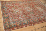 Angled view of a vintage distressed Karaja rug highlighting its faded cherry red and sapphire blue colors.