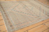Distressed Afshar rug corner with ivory abrashes, serrated brown leaf border, and dusty blue accents.