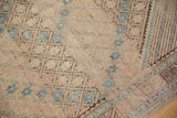Faded ivory and blush tones, blue starbursts, and brown serrated border detail of distressed Afshar rug.