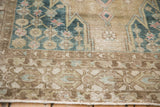 Distressed Mazlaghan rug detail: dusty ochre border, blue palmette lattice, and visible knot heads.