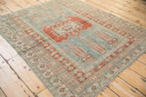 Angled view of a distressed Oushak rug showcasing its red geometric medallion on a faded blue field.