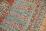 Angled detail of a vintage Oushak rug's time-softened texture and geometric patterns in red and blue.